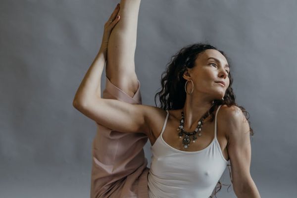 Person in a gentle stretching pose in a spacious studio.